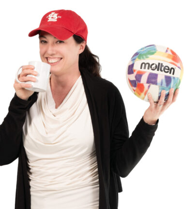 Jill Davis holding coffee mug and volleyball wearing Cardinals hat