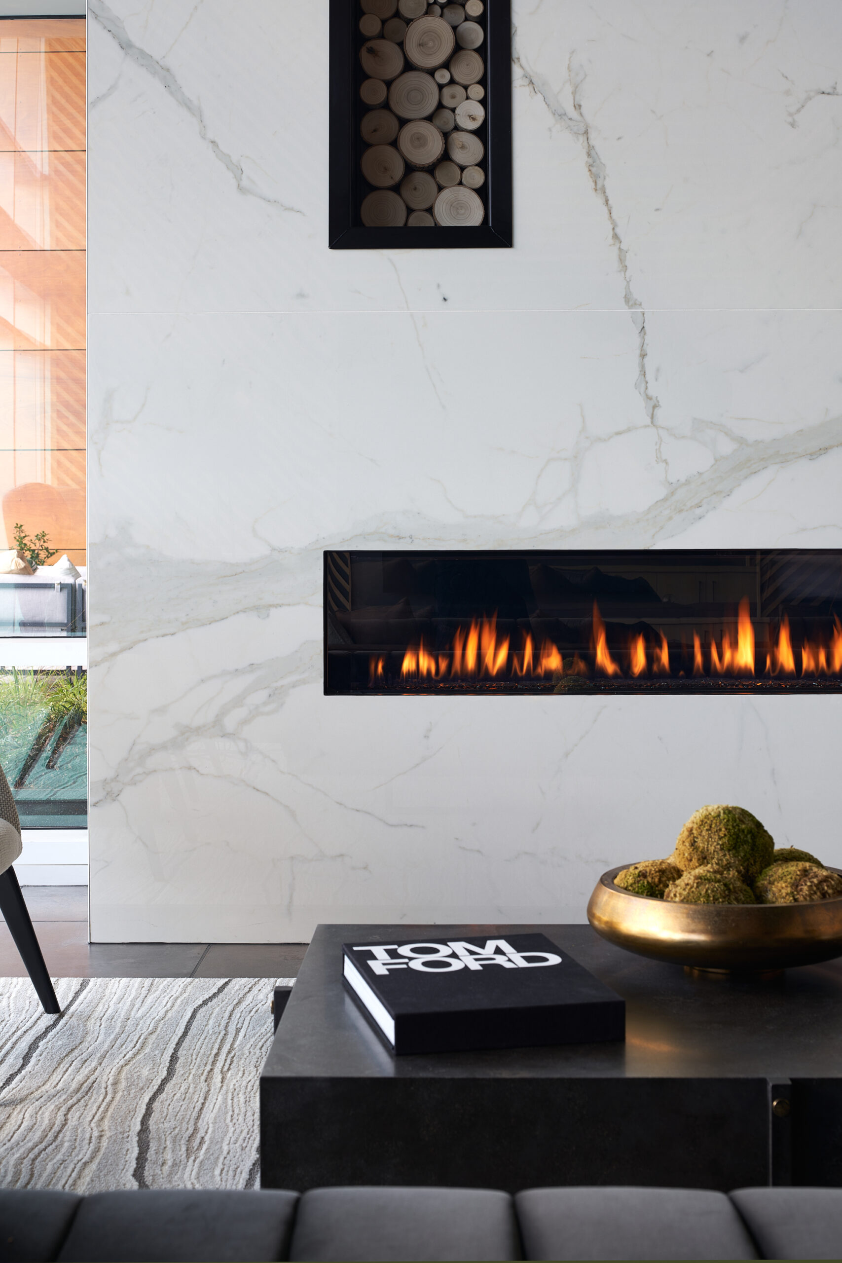 Lit fire place in marble wall behind coffee table with Tom Ford book